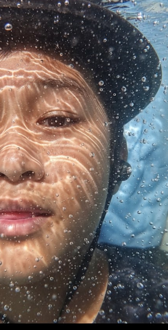 Hyper-realistic, ultra-detailed close-up portrait showing only the left half of my face submerged in