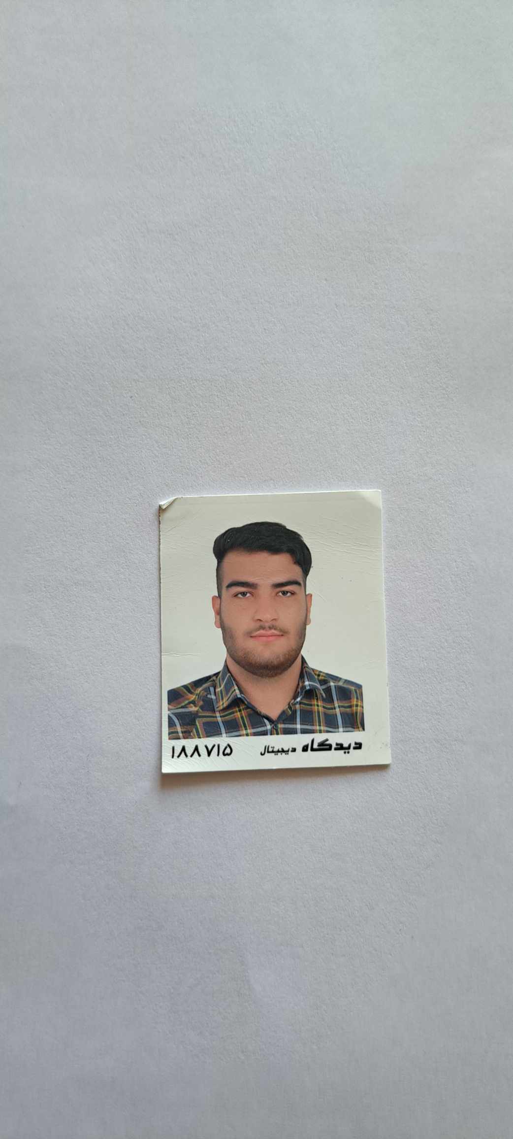 Ultra-realistic black-and-white studio portrait, 9:16 vertical. A stylish young man sits on a simple